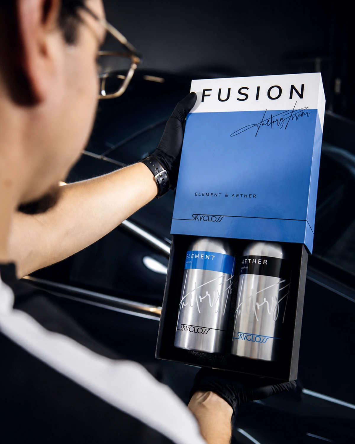 Confezione reale SkyGloss FUSION aperta con Element e Aether davanti a un veicolo scuro